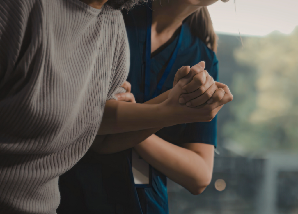 Close-up of a caregiver helping a client to stand