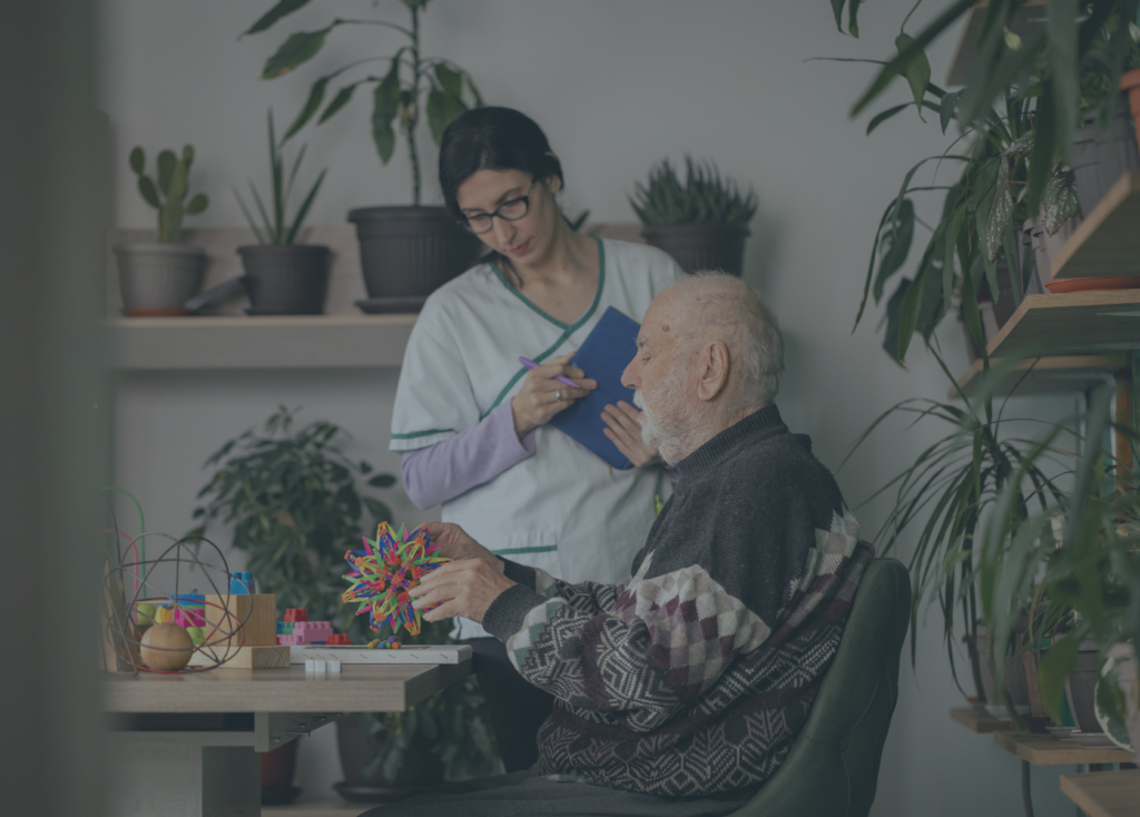 Caretaker standing with a senior man sitting at a table, doing brain exercises
