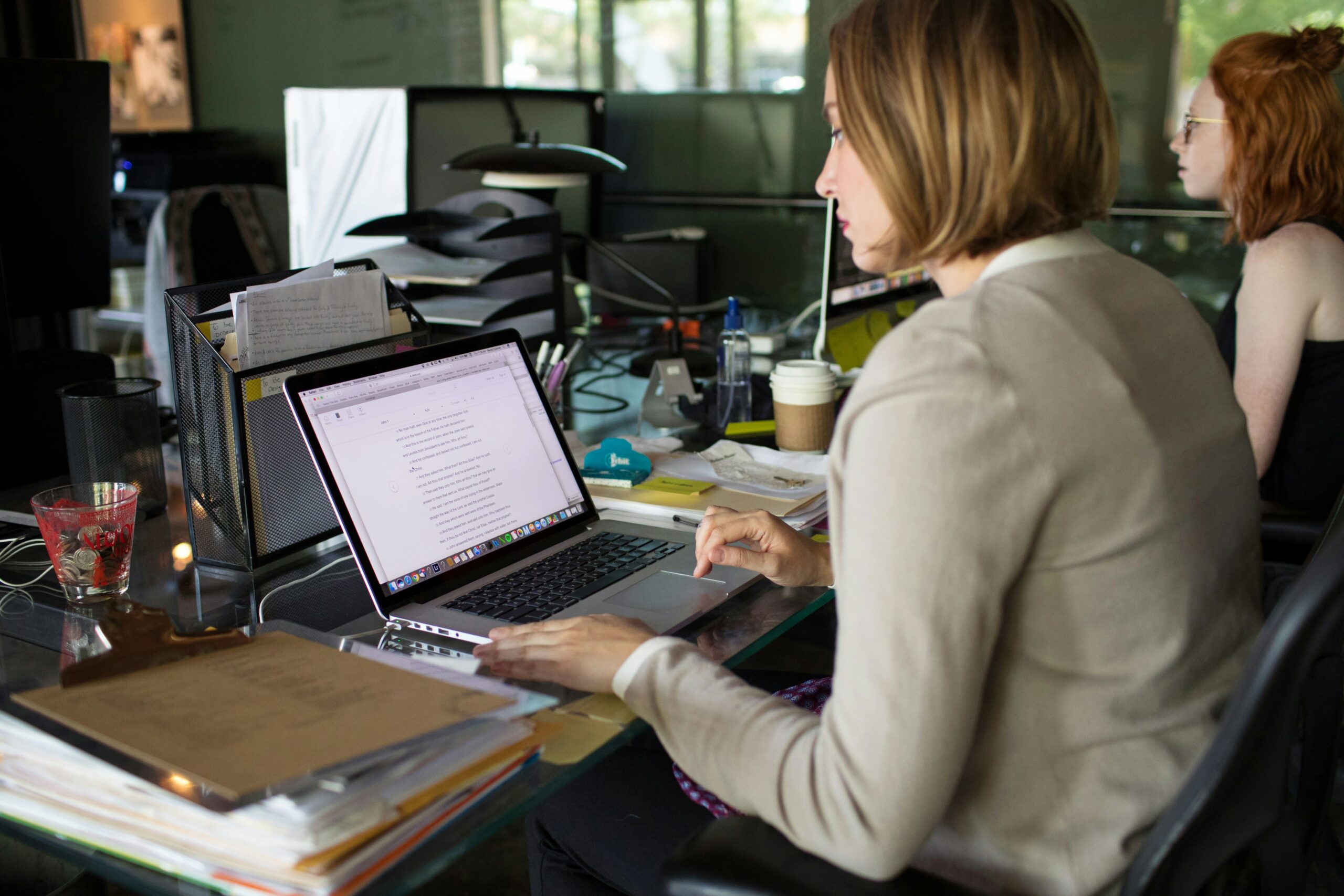 Case study hero image: two women working side by side at their desks in an office