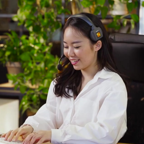 Woman wearing headset, sitting at a desk in front of a computer
